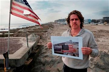(AP Photo/Mark Lennihan). In this photo taken Nov. 18, 2012, Glenn DiResto poses with a photograph he took after Superstorm Sandy, in the Far Rockaway section of the Queens borough of New York.